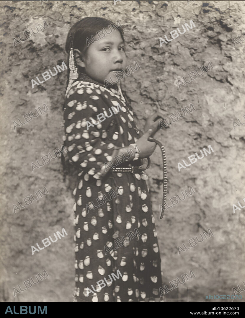 EDWARD SHERIFF CURTIS. Crow child, 1908. Photograph shows little girl, wearing traditonal dress, standing againt rock.