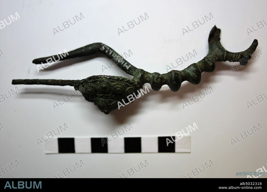 bronze LaTéne fibula (damaged). Spiral spring, needle and part of foot broken off. Bracket with lumps, back struck foot with rosette, on which spiral decoration. On either side a schematic animal head, fibula, metal, bronze, 13,1 x 3,2 x 4,0 cm, central LaTéne, Austria, unknown, unknown, unknown.