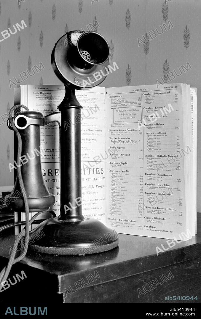Candlestick telephone and directory. Dubuque, Iowa. The candlestick telephone is a style of telephone that was common from the late 1890s to the 1940s. A candlestick telephone is also often referred to as a desk stand, an upright, or a stick phone. Photographed by John Vachon, 1940 (cropped and cleaned).