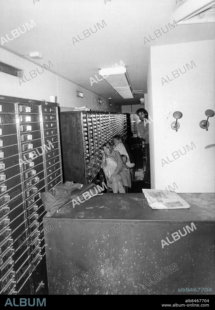 STOCKHOLM 19730823 - Under gisslandramat i Sveriges Kreditbank på Norrmalmstorg i augusti 1973 fördes Clark Olofsson av polis till banken på rånaren Jan-Erik Olssons begäran. Bilden är tagen med en kamera som sänktes ner genom ett borrat hål i taket till bankvalvet. Bilden visar gisslan Birgitta Lundblad, Sven Säfström och Elisabeth Oldgren. Stående ses Clark Olofsson. Foto: Polisen / Handout / kod 10500. **OBLIGATORISK BYLINE: Polisen / **. **Endast för redaktionell användning. Bilden kommer från en extern källa och distribueras i sin ursprungliga form som en service till våra abonnenter**.
