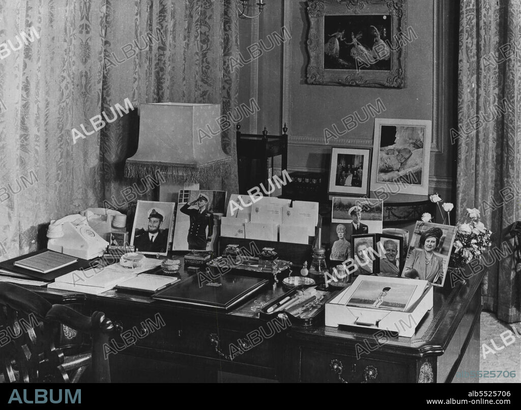 Clarence House -- Her Royal highness's Writing desk in her Royal Highness's Sitting room is of the Chippendale period. The photographs comprise H.M. The Queen H.M. Queen Mary, Princess Margaret and sever of Prince Phillip including one taken during the war when he wore a beard. Beyond are photographs taken at the Christening of Princes Charles and a painting of the ballet La Las des Cygnes by Oliver Massel. February 23, 1952.