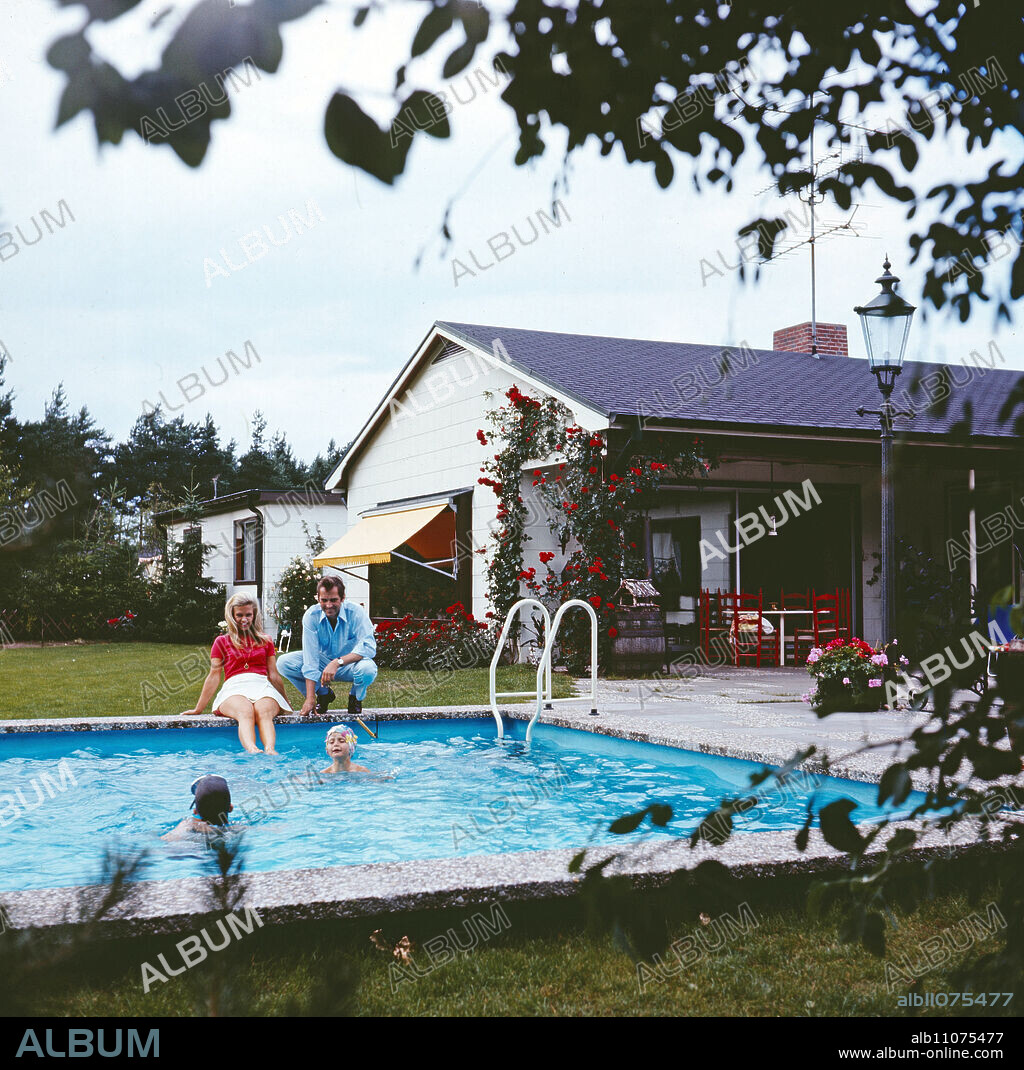 Carlheinz Hollmann, German television and radio presenter, privately with his wife Gerti Daub, the former Miss Germany, and with their two children at the swimming pool in front of his house in Hamburg, Germany, circa 1969.