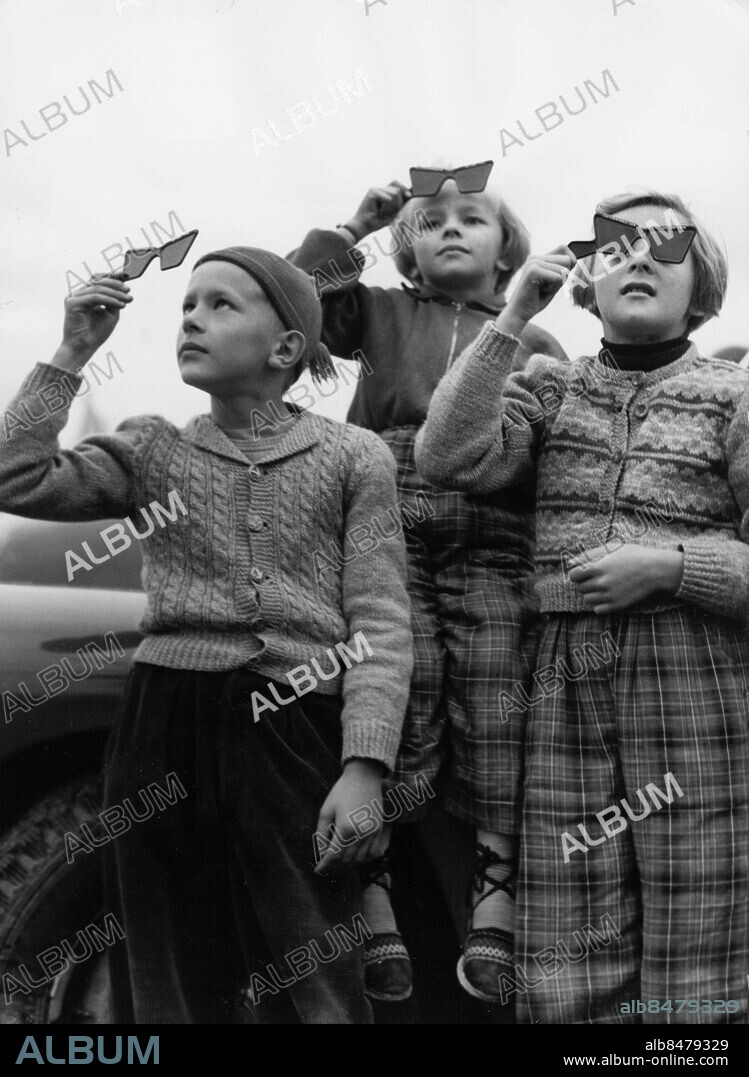 Orig. bildtext... SOLFÖRMÖRKELSE I JÖNKÖPING studerades livligt av unga som gamla. Syskonen Kjell, Inga-Britt och Valborg tittar på skådespelet. Anm. Sotade glas Stickade tröjor Mönster Rutiga byxor sites: JÖNKÖPING;SVERIGE.