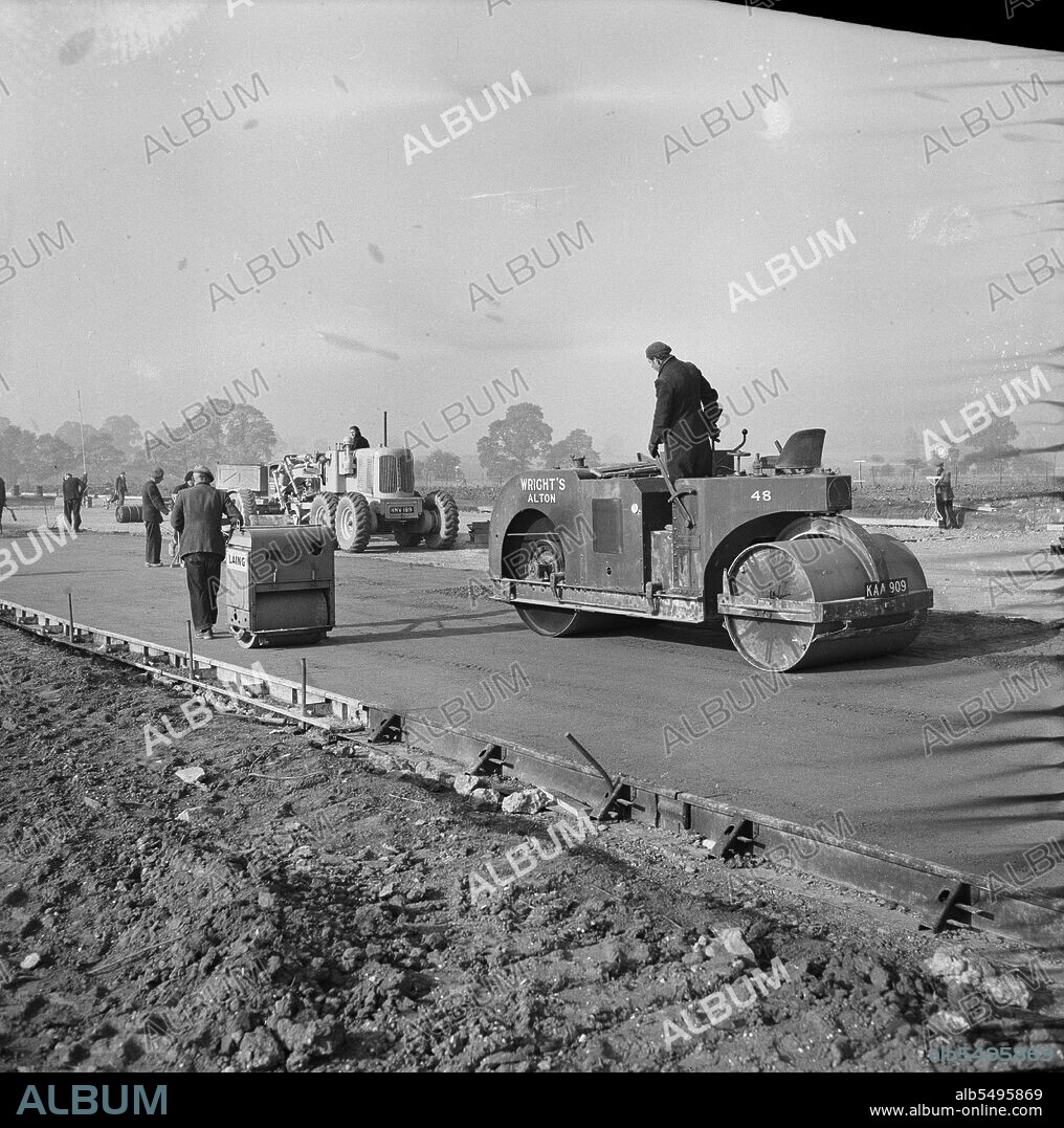 JOHN LAING PLC. RAF Gaydon, Gaydon, Stratford-on-Avon, Warwickshire, 11/10/1952. Work underway on the construction of a new runway at Gaydon Airfield, showing a Wright's roller and a pedestrian roller compacting the concrete working course. Work began on the construction of a runway at Gaydon Airfield in early 1952. As part of the project, a former runway, largely abandoned following the Second World War, was superseded by a newly constructed runway nearly 1 3/4 miles long and 200 feet wide. Also built were access tracks and a taxi-track. The runway was constructed on 8 inches of hardcore, with four inches of concrete laid on top, followed by 12 inches of high grade concrete, and completed with 2 1/2 inches of tarmacadam and 1 1/2 inches of bituminous macadam. This photograph was published in the March 1953 edition of 'Team Spirit', the Laing employee newsletter.