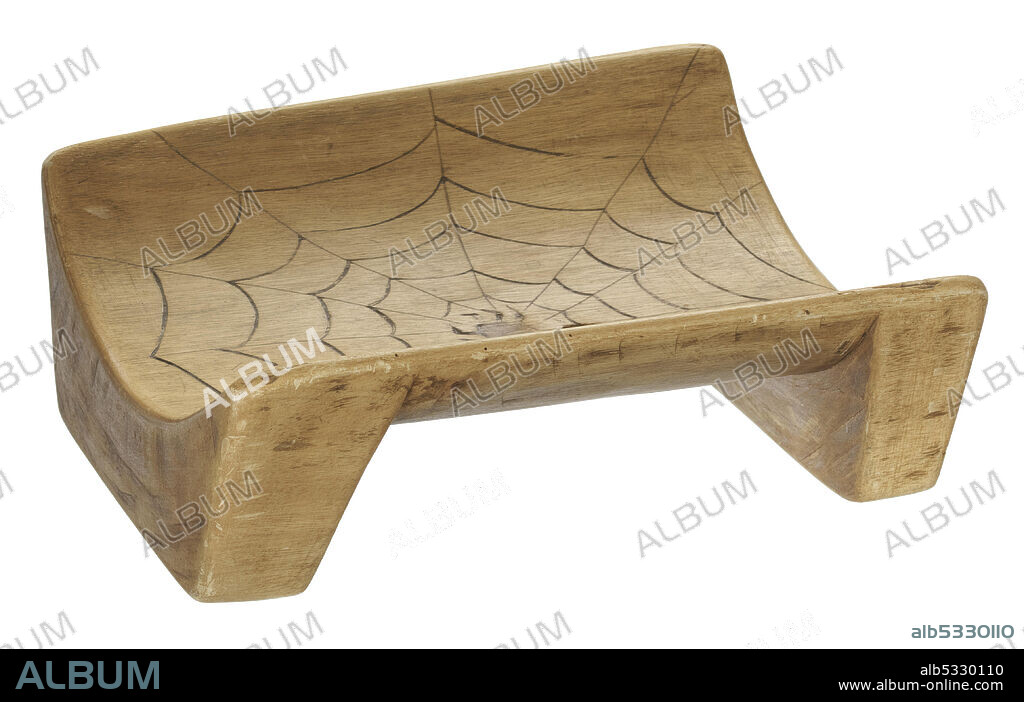 A carved wooden boat seat with two legs and a concave center. The seat has a design etched into its surface of a spider web. A spider is at the center of the web.