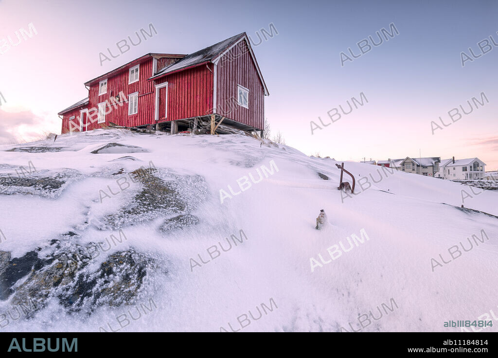 Pink sky on the typical red house of fishermen (rorbu), Henningsvaer, Lofoten Islands, Arctic, Northern Norway, Scandinavia, Europe.