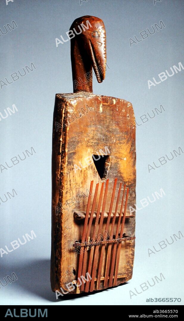 Kisanji (Cisaji). Culture: Bateke. Dimensions: 17 × 3 1/2 in. (43.2 × 8.9 cm). Date: late 19th century.
This Kisanji (Cisaji), decorated with a carved bird's head is a Lamellaphone.
Lamellaphone is a term to designate instruments consisting of thin tongues of metal or split cane, mounted on a resonating board or box. Depressing the free ends of the tongues with the thumbs produces a gentle ringing sound, sometimes augmented by jingling objects attached to the board, and amplified by holding the instrument in a hollow gourd. Tuning is accomplished by sliding the tongues in or out in order to change their vibrating length. Lamellaphones are distributed across sub-Sahara Africa and were brought by slaves to Latin America. They are known by many names that may also be shared with xylophones. Most names have word stems which include: -mbila; -mira; -limba; or -rima. Westerners, not recognizing differences in construction, have simplified the name to two regional terms calling them either mbira or sanza.