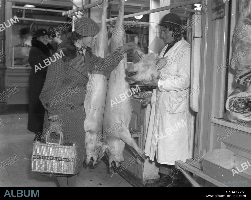 Göteborg 1935-12-11 - Saluhallen - Julmat - En kvinna får hålla i örat på en julegris - grishuvud - *** Local Caption *** GT Låda 1935-december-02. KAMERAREPORTAGE.