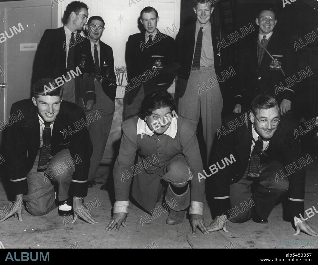 Famous English comedian, Sid Field, skylarks at Denham studios with Australian Olympic athletes John Treloar (left) and Bill Bruce. August 29, 1948. (Photo by Dennis Reed).