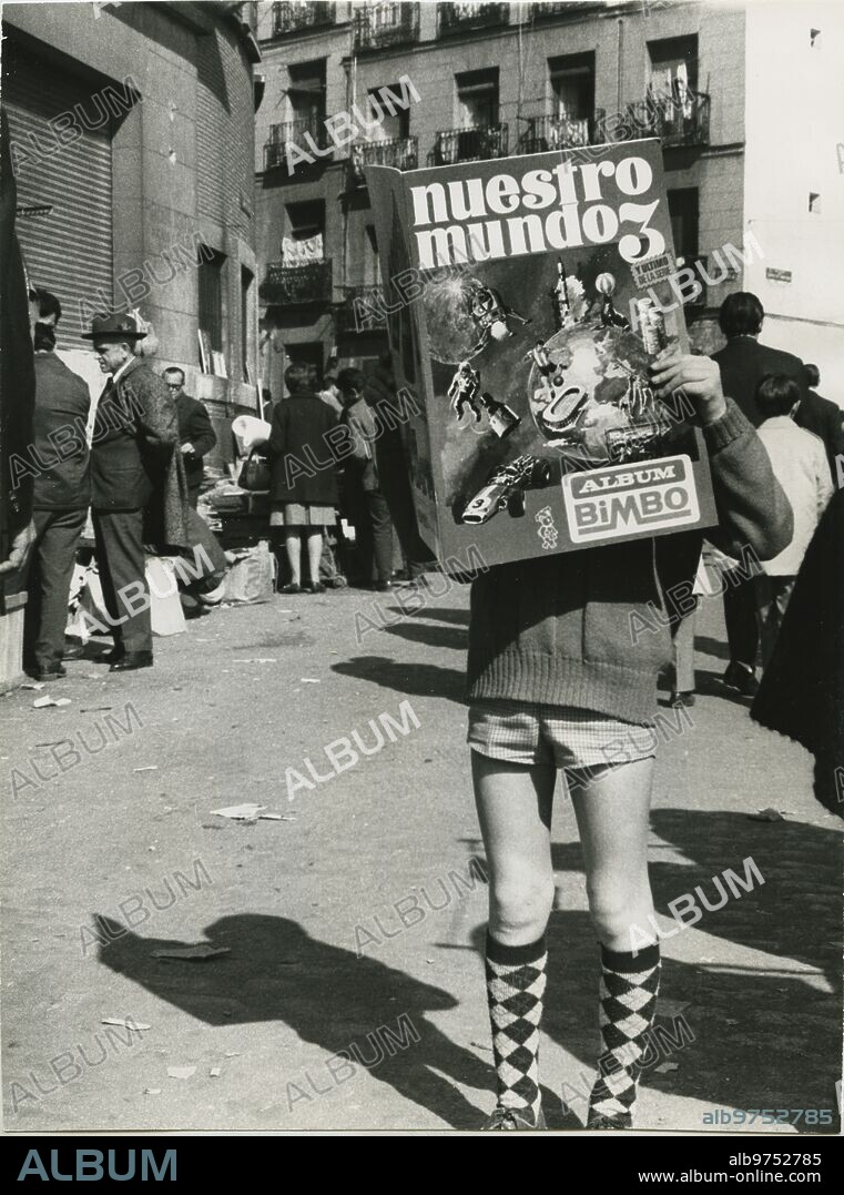 Madrid, 1969 (CA.). Niño ojeando el libro de cromos de Bimbo en la Plaza del Campillo del Nuevo Mundo.