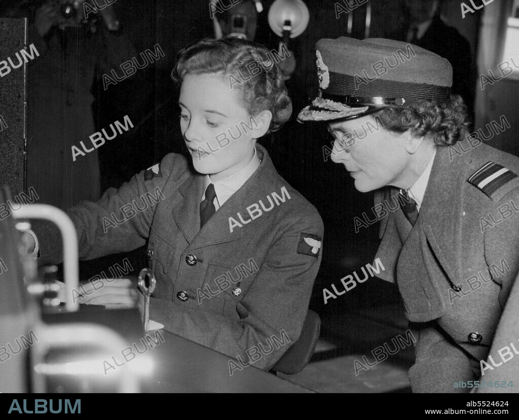 Duchess In Spectacles -- The Duchess of Gloucester wearing spectacles to get a better view of the equipment as Aircraft woman Beryl Thompson,  Women's Royal Air Force, explains some of the apparatus in a static exhibition inspected by the Duchess during her visit to-day (Friday) to Headquarter No. 90 (Signals) Group, RAF, at Madmenham, Buckinghamshire.The Duchess, in uniform as Air Chief commandant of the Women's Royal Air Force, was shown in the exhibition the technical work of airwomen and the important role played by the WRAF in the RAF signals organisation. November 12, 1954. (Photo by Reuterphoto).