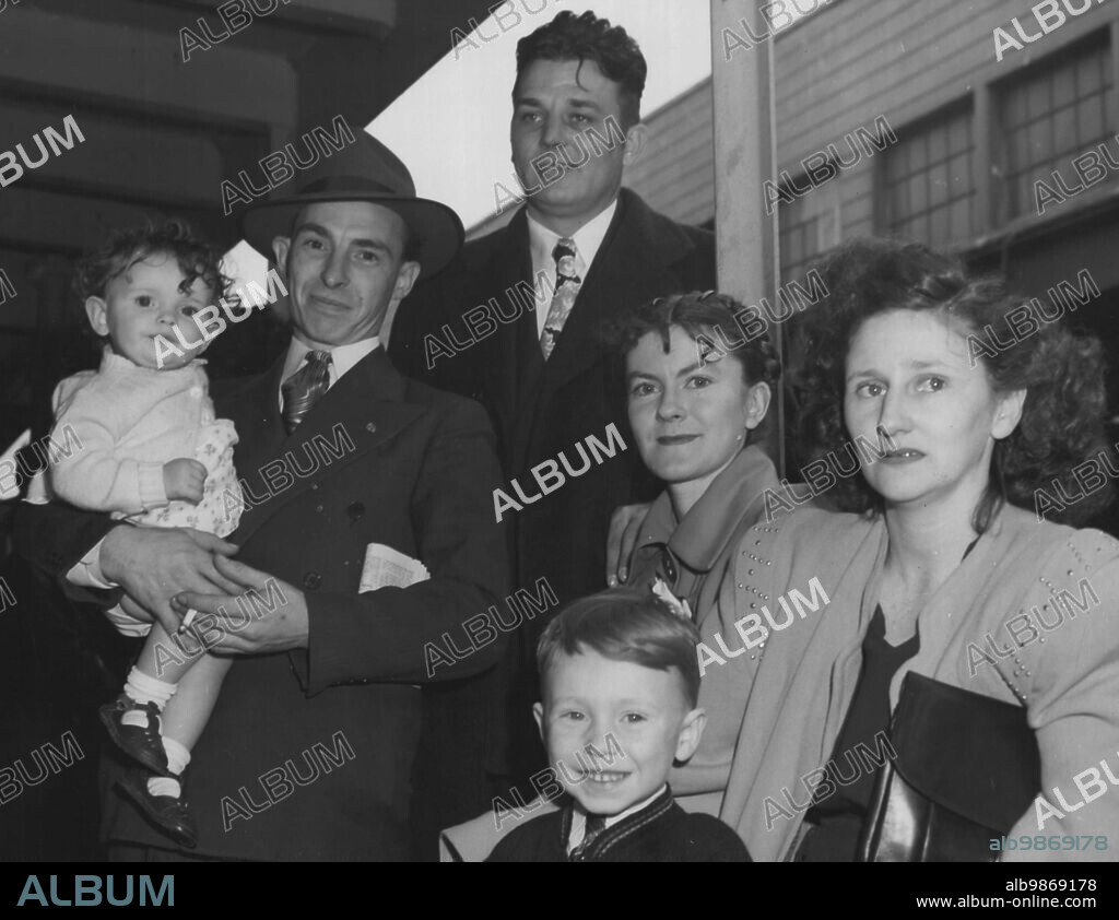 Migrants For Australia - Among the 210 American ex-servicemen and their families who sailed from San Francisco for Australia on the Marine Phoenix, May 16, 1948 were: Front: Mr. Ovila Langevin holds his daughter Adele (1 yr) with their son Henry (4 yrs.) The Langevins are from West Warwick, Rhode Island and are on their way to Cairns, Queensland, Mrs. Lanevins former home. Adept at many crafts, Mr. Langevins intends to concentrate on Watchmaking. Rear: Richard N. Turner Jrn. (27) ann his wife Amy (24) are from Waco, Texas, and intend to make their future home in Yarloop, Western Australia, Mrs. Turner's former home. Mr. Turner intends to base his career on his experience as Navy photographer. June 11, 1948. (Photo by Phyllis Pozzesi).