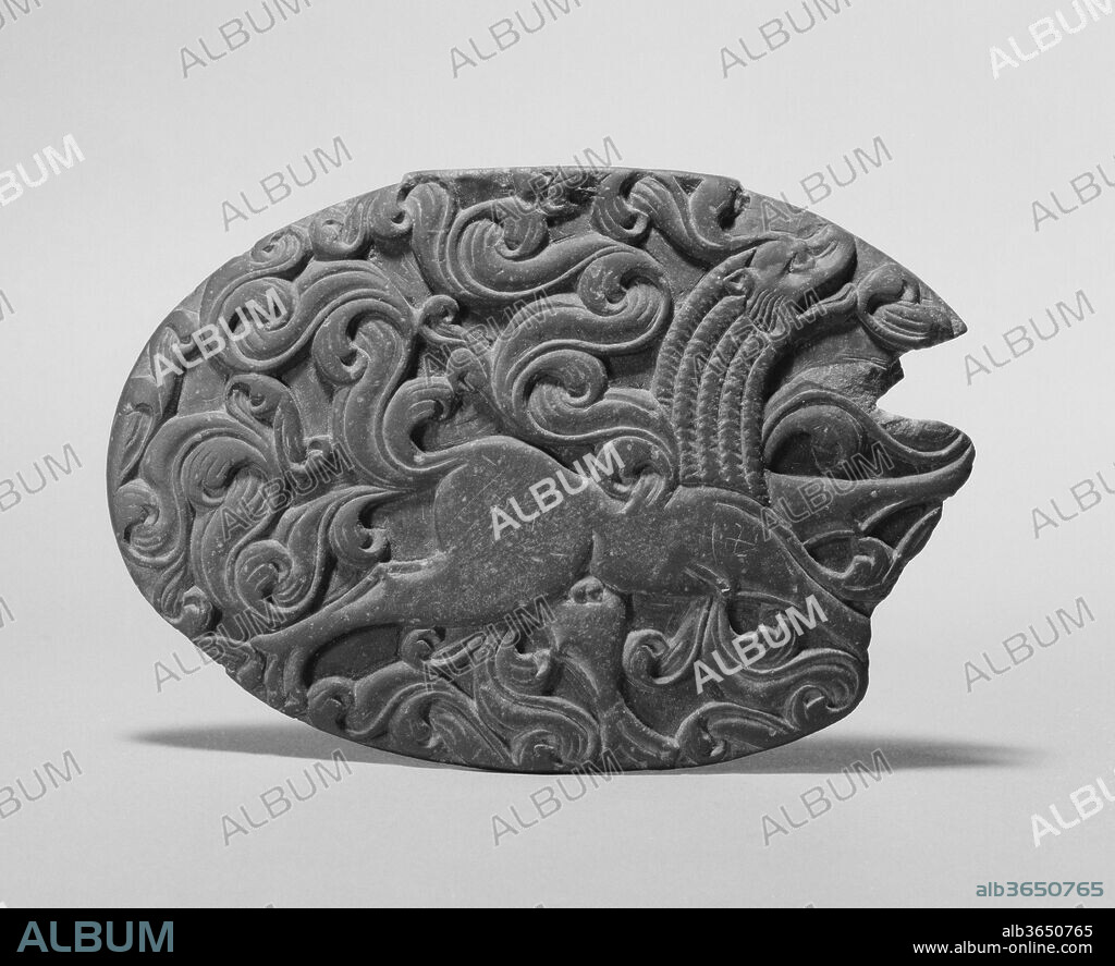 Box Lid with a Winged Lion and Remnant of an Iron Hinge. Culture: Pakistan (ancient region of Gandhara). Dimensions: W. 4 3/8 in. (11.1 cm). Date: ca. 5th century.
Box lids are rare examples of nonreligious art of the fifth century, little of which has survived. They are closely related in style and imagery. Their dating is based on the decorative scrolls of the Gupta period.