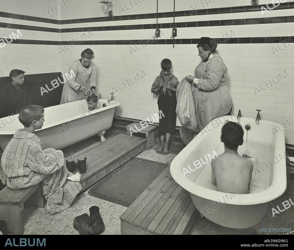 Attendants bathing boys at the Sun Court Cleansing Station, City of London, 1914. Sombre scene of women and boys in a tiled bathroom. At this time many people had no bathroom at home.