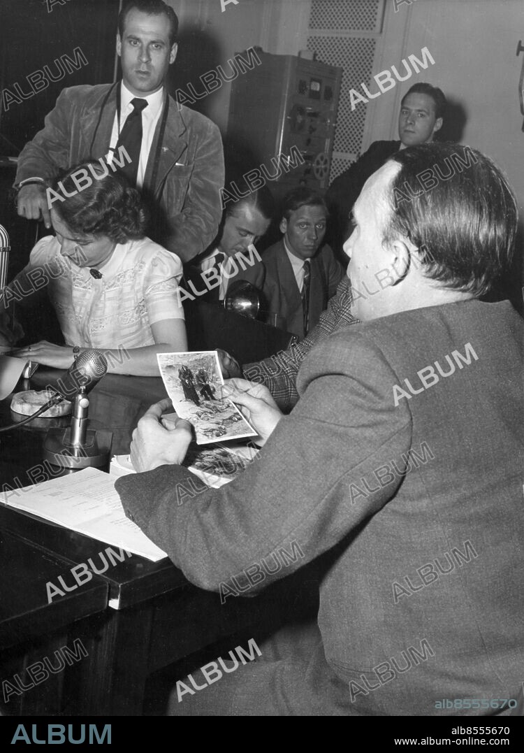 Orig. bildtext... FOREST MASSACRE INQUIRY MOVES INTO GERMANY. The inquiry by U.S. Congressional Committee into the Katyn Forest Massacre of Poles, which was held in secreet in London, has now moved to Germany, where hearings have opened at Frankfurt. The committee is investigating whether the Germans or the Russians were responsible for the murder of 4,200 Polish officers and civilians found buried in the forest near Smolensk, Russia. PHOTO SHOWS. Dr Tromsen, a Danish pathologist was heard as a witness, he was a member of the international committee in 1943 and corroborated the fact that the condition of the bodies indicated that they undoubtedly were murdered in 1940 and not during the summer 1941 as the Soviets claimed. Tromsen presented a picture showing himself and German Officers standing at the graves in Katyn in 1943, which he is seen holding. anm. cd 231 Krigsförbrytelser sites: FRANKFURT;TYSKLAND.