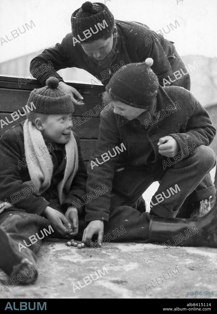 Stockholm 1955-03-17. Lekande barn. De som spelar kula med tärning heter från vänster Per Löpare, Jan Roos och Eneriko Boneli. Det förefaller som om Per vann just då.. Foto: DN / TT / Kod: 192. ** SvD OUT **.