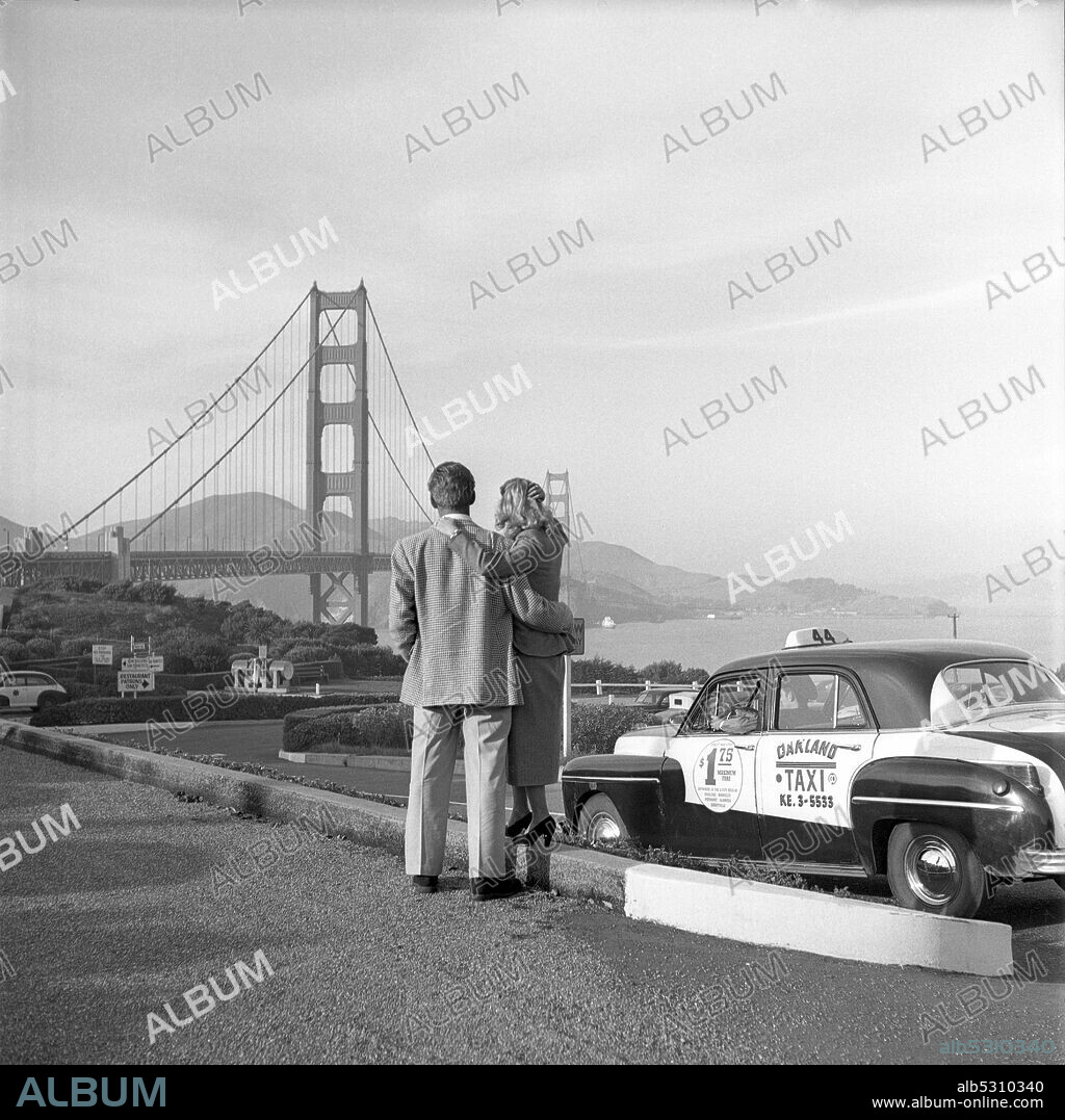 FORREST TUCKER. Circa 1951, San Francisco, California, USA: 40's and 50's movie star FORREST TUCKER enjoys the view of the San Francisco Bay and Golden gate bridge with his girlfriend.