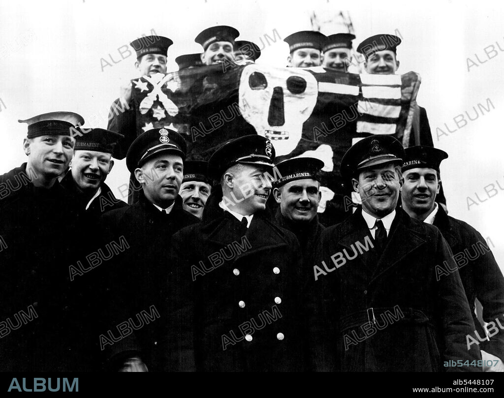 "***** Thrasher" - The "Double V.C." Submarine Returns After Eventful Voyage -- Petty Officer Gould, V.C. with scene of the crew on arriving in port. Note their 'Jolly Roger' flag; ***** Submarine "Thrasher" under the command of Lieut, H.S. Mackenzie, D.S.O. R.N. has just returned to port known as the "Double V.C." submarine, ***** the 'Lucky 13' Submarine, She was commissioned for service on April 13th 1941, was sunk a 3,500 ton supply ship on April 13th, 1942, and on the same day included among her trophies a picture of Hitler taken from an Axis supply ship which a party from the Thrasher boarded before sinking. The Victoria Cross was awarded to Lieut. P.S.W. Roberts R.N. and Petty officer T.W. Gould (then first Lieutenant and Second Coxswain respectively) for great valour while serving in H.M.S. Thrasher. January 07, 1943.