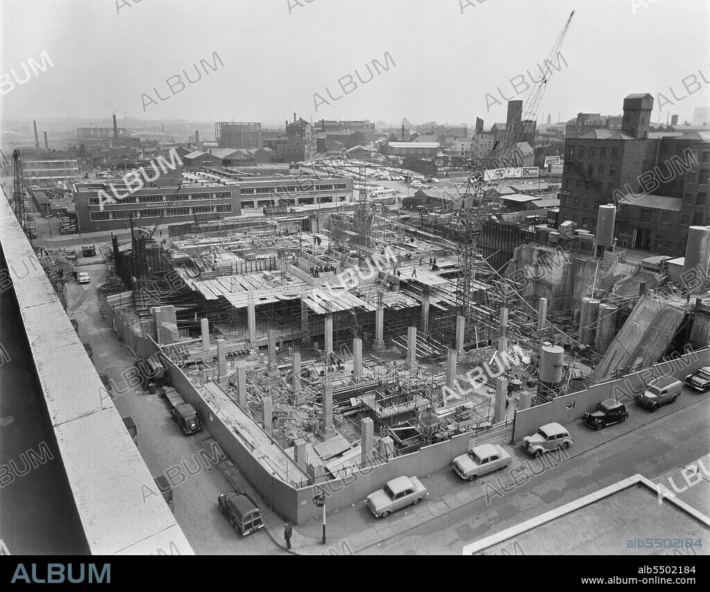 JOHN LAING PLC. CIS Building, Cooperative Insurance Society Tower, Miller Street, Manchester, 25/05/1960. Looking north-east over the Co-operative Insurance Society (CIS) Building during construction, showing the ground floor slab over the deep basement section. The caption beneath the corresponding print of this image reads: "Foreground columns ready to receive floor slab were built off an existing air raid shelter roof. Weitz G60 and Buildmaster Tower Cranes are in use over the deep basement and shelter roof sections respectively. Concrete mixing plant can be seen in the right of the photograph.".