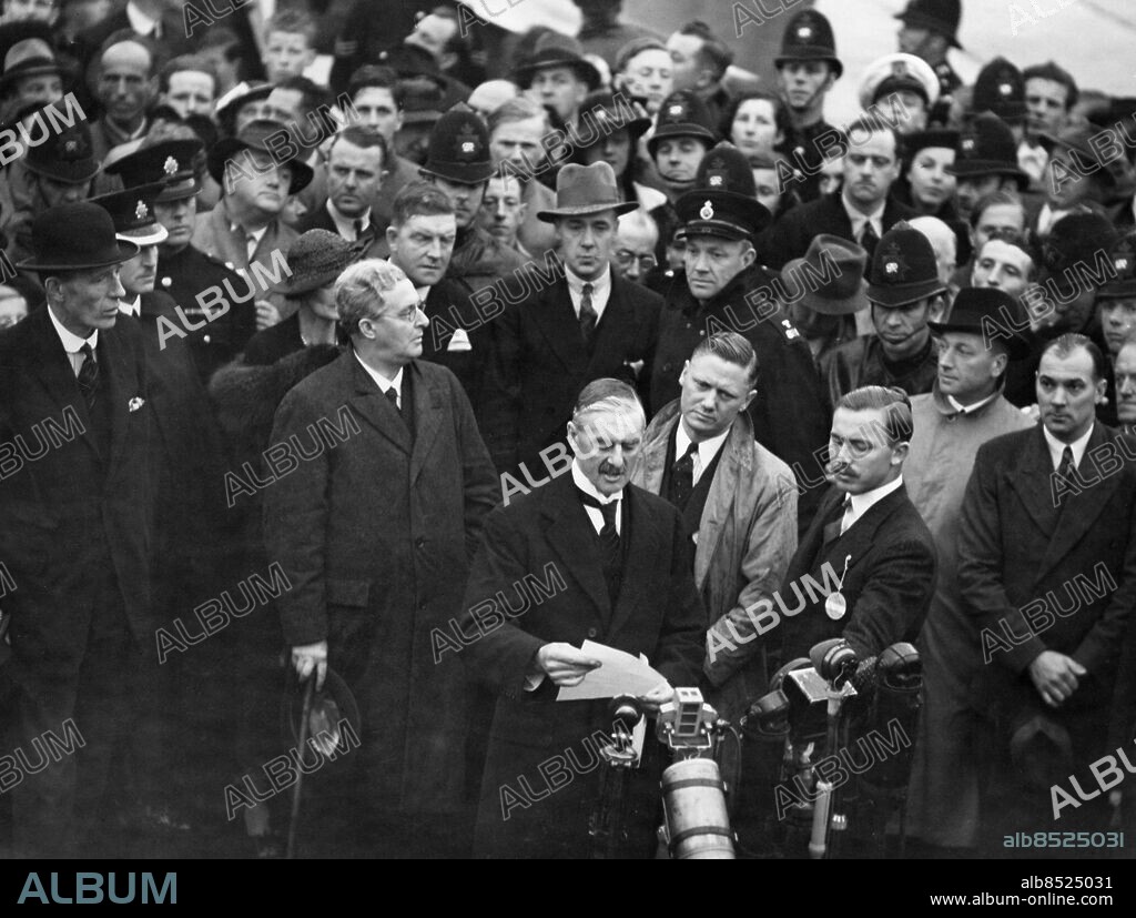 Orig. bildtext... PREMIER'S TRIUMPHAL RETURN AFTER FOUR-POWER PEACE CONFERENCE AT MUNICH PREMIER READS TREATY TO CROWDS Photo shows: Mr. Neville Chamberlain, the Prime Minister, reading the contents of the Anglo-German Peace Treaty to the waiting crowds, on his arrival at Heston airport this evening from Munich. Anm. Münchenöverenskommelsen - avtal mellan Tyskland, Storbritannien, Frankrike och Italien 29/9 1938, vilket resulterade i att Tjeckoslovakien tvingades avträda vissa delar av Böhmen och Mähren, de s k Sudetområdena, till Tyskland Münchenkrisen CD111 persons: Neville Chamberlain sites: STORBRITANNIEN.