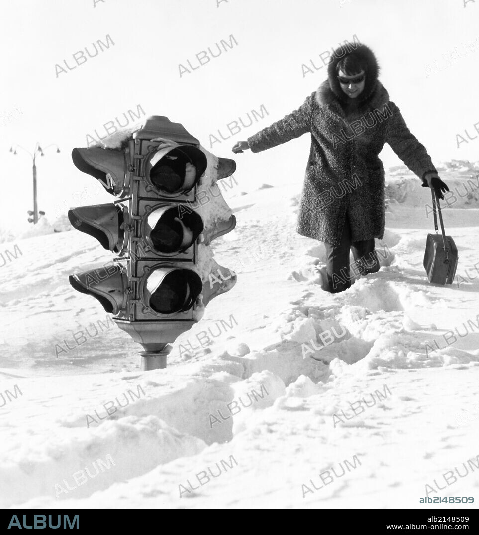 A woman walking by a traffic light on a huge snow drift after a five-day blizzard in yuzhno-sakhalinsk in the southern part of the soviet island of sakhalin, february 1970.