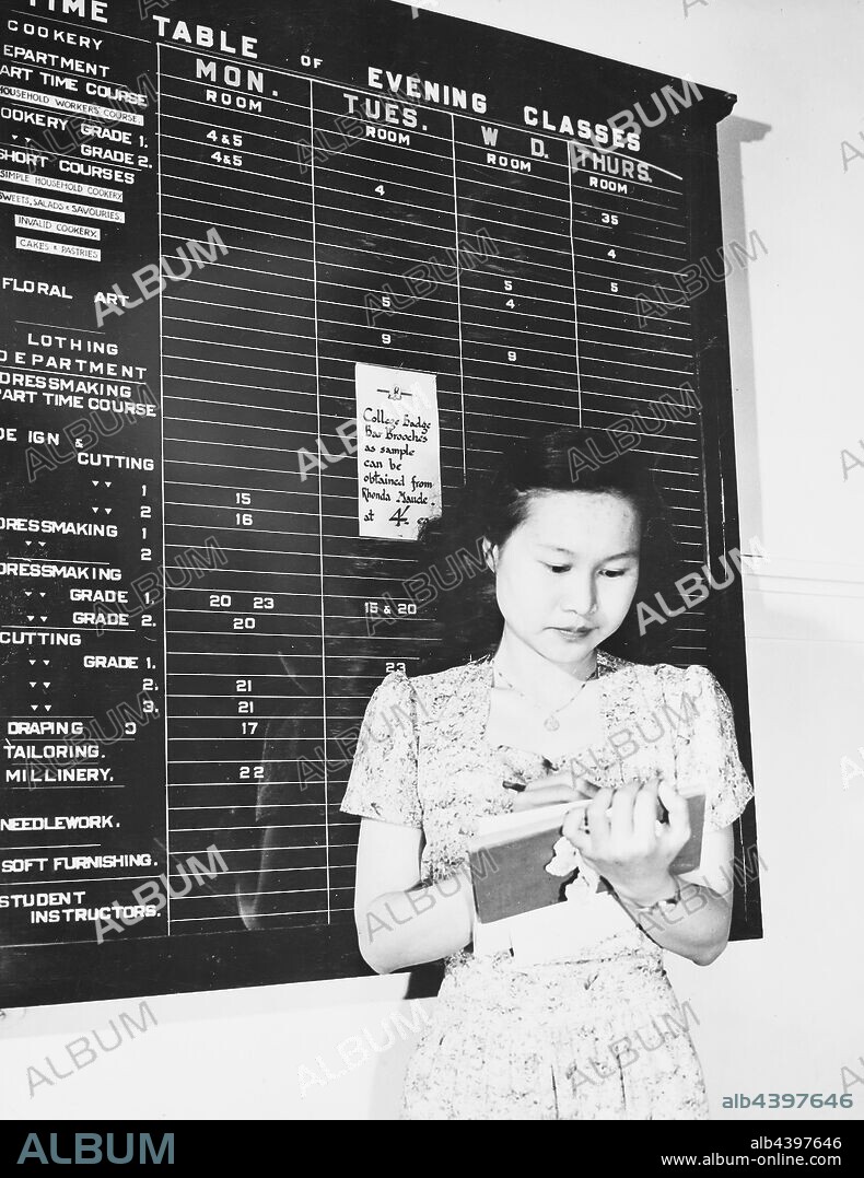 Negative - Emily McPherson College, Timetable of Evening Classes, circa 1950, Negative photograph of a student in front of a notice board at the Emily Mcpherson college. The noticeboard provides a 'Timetable for evening classes', including cookery, floral art, dressmaking, tailoring, millinery, needlework and soft furnishing. A notice adhered to the board names Rhonda Maude as the source for 'college badge bar brooches'. Rhonda Maude was vice-president of the student.