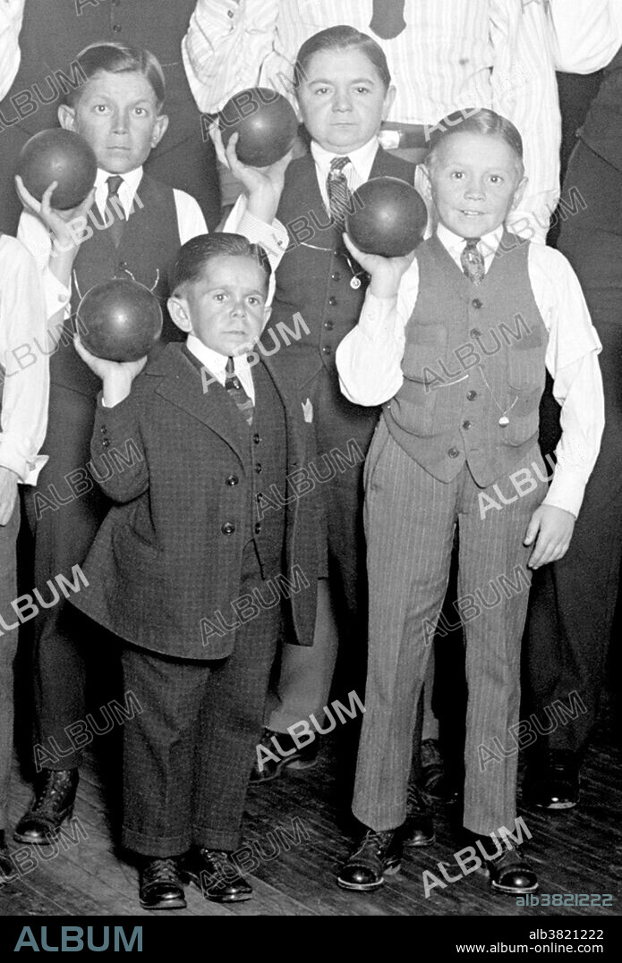 Entitled: "Singer's Midgets Bowling at YMCA." Singer's Midgets were a popular vaudeville group in the first half of the 20th century. Leopold von Singer (May 3, 1877 - March 5, 1951) formed Singer's Midgets in 1912-13, and built the Liliputstadt, a "midget city" at the "Venice in Vienna" amusement park, where they performed. The Liliputstadt was a major success, Singer began to tour with his performers throughout Europe and, in the process, recruited new members. After WWI broke out, the troupe traveled to the United States, and remained there for the remainder of their existence where they performed in vaudeville theaters. During the 1930s, some of Singer's Midgets began appearing in films, most notably, The Terror of Tiny Town and The Wizard of Oz. The Singer Midgets disbanded in the mid-1940s, with many members returning home to their native Europe. Photographed by National Photo Company, 1924.