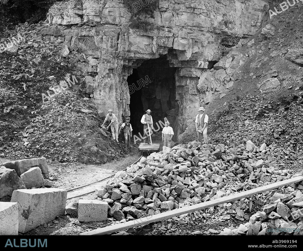 Westington Quarry, Westington, Chipping Campden, Gloucestershire,1895. Five of the quarrymen are standing posed at the entrance to the quarry, one on the trolley which carries stone from the quarry. The quarry is still in use today providing stone for paving and walls.