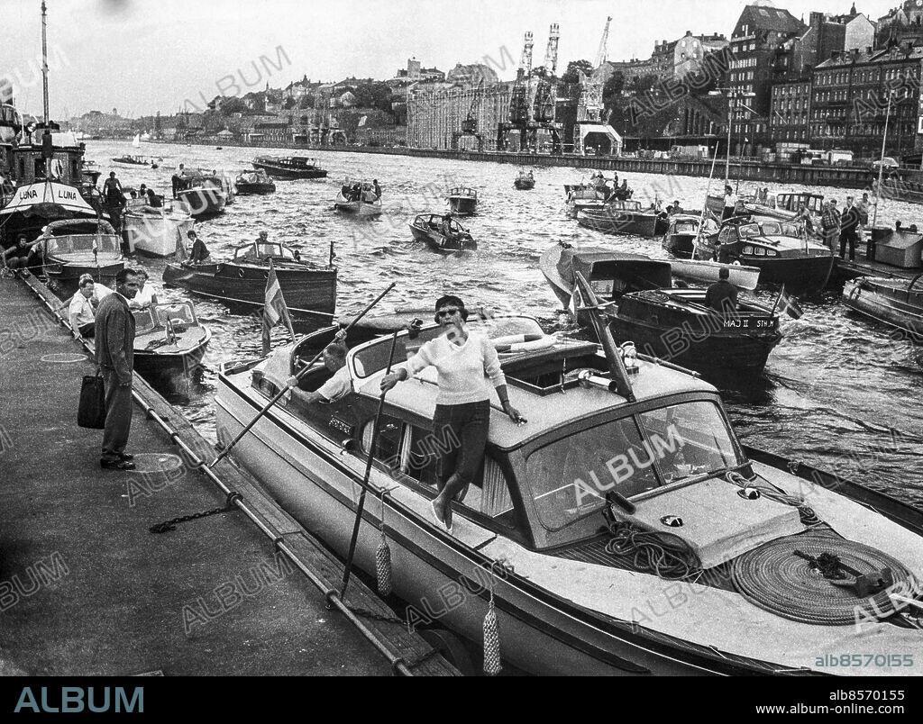 Stockholm 1959-08-17. Slussning i Karl Johan-slussen. På sista badsöndagen blev det inte bara köer på landsvägaranai Stockholm såg det ut så här när alla hemvändande motorbåtar strävade upp mot Slussen, nålsögat mellan Saltsjön och Mälaren. Kapaciteten i Slussen är inte stor, så det blev ganska lång väntetid. Men i det härliga solskenet på eftermiddagen tog besättningarna det lugnt. Det hade inte så bråttom hem den höstdag (!) som var rena högsommardan.. Foto: Lars Nyberg / Expressen / TT / Kod: 34. ** AFTONBLADET OUT **.
