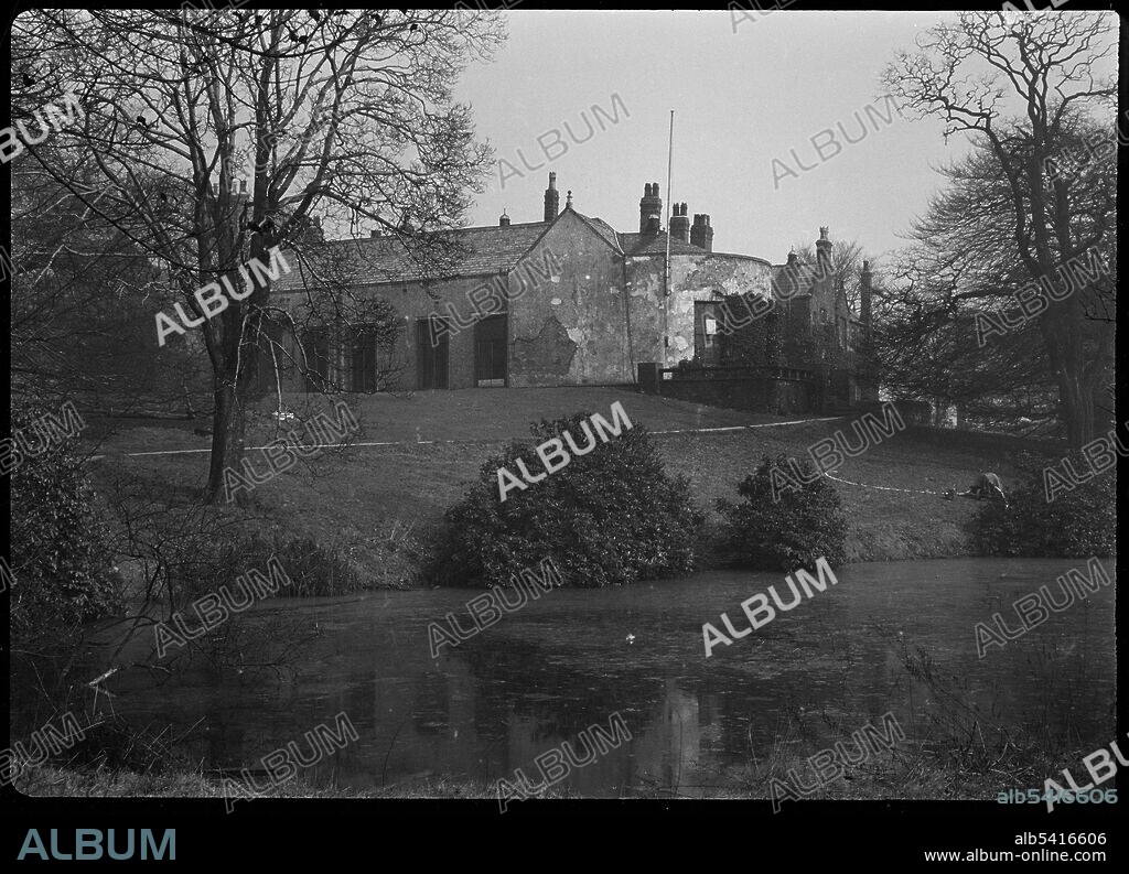 GEORGE BERNARD WOOD. Barlow Hall, Barlow Hall Road, Chorlton Cum Hardy, Manchester, 1942. An exterior view of Barlow Hall, seen from the south-west in the grounds, with a moat in the foreground. Formerly a manor house, Barlow Hall was built in the 16th and 17th centuries, with alterations made in the 18th, 19th and 20th centuries. It was badly damaged by a fire in 1879 and formerly consisted of four ranges surrounding a courtyard. Now, there are three ranges of two storeys, with the east side of the courtyard open. The south range has a large semi-circular bay at the west end with French windows, and the west range has an earlier gabled bay at the north end, with the rest covered with a 20th century loggia.The house was the home of Blessed Ambrose Barlow (b.1585 and martyred at Lancaster 1641), and is now a golf club.
