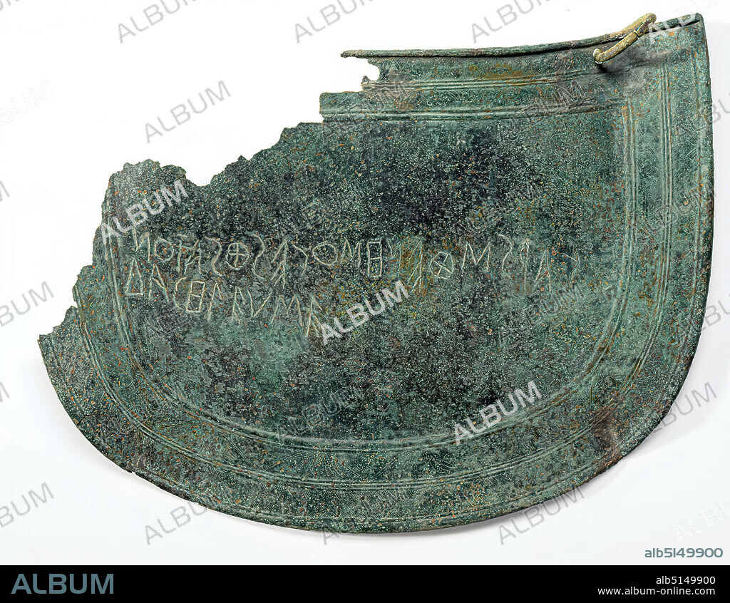 Mitre with inscription, bronze, chased, engraved, punched, bronze, total: height: 17 cm; width: 23 cm, inscription: Front: | , protective clothing, armor (warfare/military), weapons (warfare/military), ritual objects and accessories, votive offerings, burial objects, ornaments, lotus ornament, early archaic, Greek antiquity, The mitre is an arch-shaped protective plate for the abdomen, whose convex forged rounding corresponds to the shape of the human abdomen. They seem to be a Cretan peculiarity. Suspended from rings, miters were probably attached to a belt worn under the protruding edge of the bell armour. The edges of miters are usually rolled around a reinforcing wire like the breast and back armour. On some, a figurative representation occupies the entire segment surrounded by the parallel bars. Here, however, there is a two-line inscription in the center. This is one of the oldest Greek inscriptions known. In Boustrophedon ('how the ox ploughs') the following text is engraved in the opposite direction: 'Karisthenes, the son of Peithias carried him away'. The two flat edge strips formed by the border strips contain finely carved and punched ornaments: a lotus palmette tendril and a row of teeth.