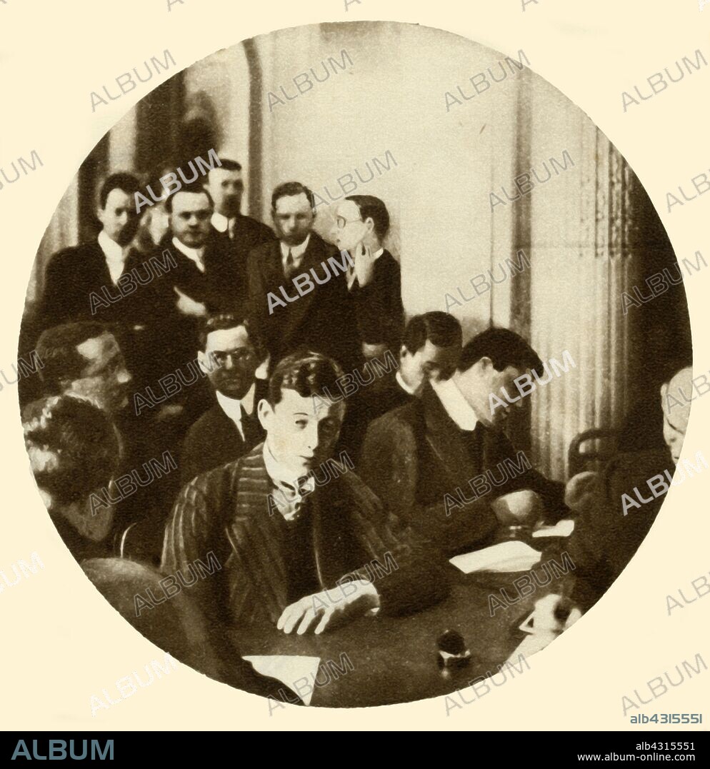 Wireless operator Harold Bride being questioned about SOS messages sent during the sinking of RMS 'Titanic', 1912, (1935). 'The wireless operator is undergoing examination as to the time the SOS messages were sent out'. Operated by the White Star Line, 'Titanic' was the largest and most luxurious ocean liner of her time, and thought to be unsinkable. During her maiden voyage, bound for New York, she struck an iceberg in thick fog off Newfoundland on 14 April 1912. In the collision five of her watertight compartments were compromised and she sank. Out of the 2228 people on board, only 705 survived. A major cause of the loss of life was the insufficient number of lifeboats she carried. From "The Silver Jubilee Book - The Story of 25 Eventful Years in Pictures". [Odhams Press Ltd., London, 1935].