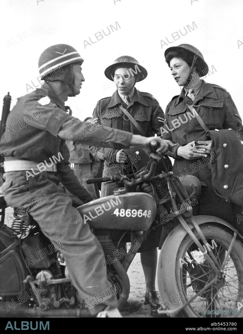 First A.T.S. Arrive in Normandy - Lance Corporal E. Martin A. Military Policeman talking to Corporal Joyce Collins of Norwich and Lance Corporal Cella Strong of Plumstead. Both these girls will act as M.P.'s in Normandy. The first party of A.T.S., have just arrived in Normandy, they will be attached to 21st., Army Group. Their duties will be to act as clerks in the beachhead. These pictures show the first party of 24 arriving by landing craft at one of the Normandy beaches. October 23, 1944.