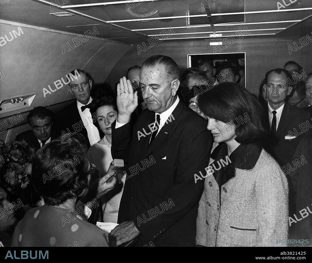 Swearing in of Lyndon B. Johnson as President. Left to right: Mac Kilduff (lower left corner), Jack Valenti, Judge Sarah T. Hughes, Congressman Albert Brooks, Lady Bird Johnson, Chief Curry (behind LBJ's hand), President Lyndon B. Johnson, Evelyn Lincoln (eyeglasses only visible behind LBJ), Jacqueline Kennedy, Congressman Jack Brooks. Johnson was sworn in as President on the Air Force One plane at Love Field in Dallas on November 22, 1963, just 2 hours and 8 minutes after John F. Kennedy was assassinated in Dallas, amid suspicions of a conspiracy against the government. He was sworn in by U.S. District Judge Sarah T. Hughes, a family friend, making him the first (and so far only) President sworn in by a woman. He is also the only President to have been sworn in upon Texas soil. In the rush, a Bible was not at hand, so Johnson took the oath of office using a Roman Catholic missal from President Kennedy's desk. Johnson being sworn in as president has become the most famous photo ever taken aboard a presidential aircraft. He was convinced of the need to make an immediate transition of power after the assassination to provide stability to a grieving nation under shock. In the days following the assassination, Lyndon B. Johnson made an address to Congress saying that "No memorial oration or eulogy could more eloquently honor President Kennedy's memory than the earliest possible passage of the Civil Rights Bill for which he fought so long." Photographed by Cecil Stoughton.