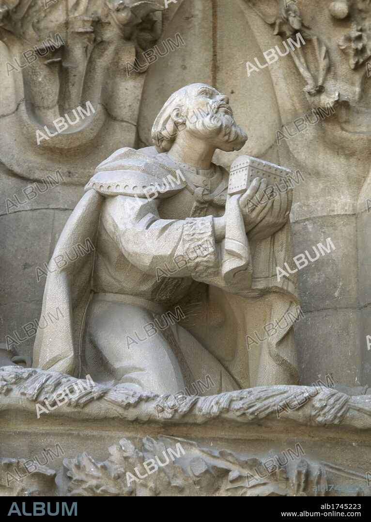 Antoni Gaudi Cornet (1852-1926). Spanish architect. Basilica and Expiatory Church of the Holy Family. Nativity Facade. 1894-1930. Portico of Charity. Adoration of Magi. Detail.  Melchior offers gold.(1981-1982). By Joachim Ros Bofarull (1906-1991). Barcelona. Catalonia. Spain.