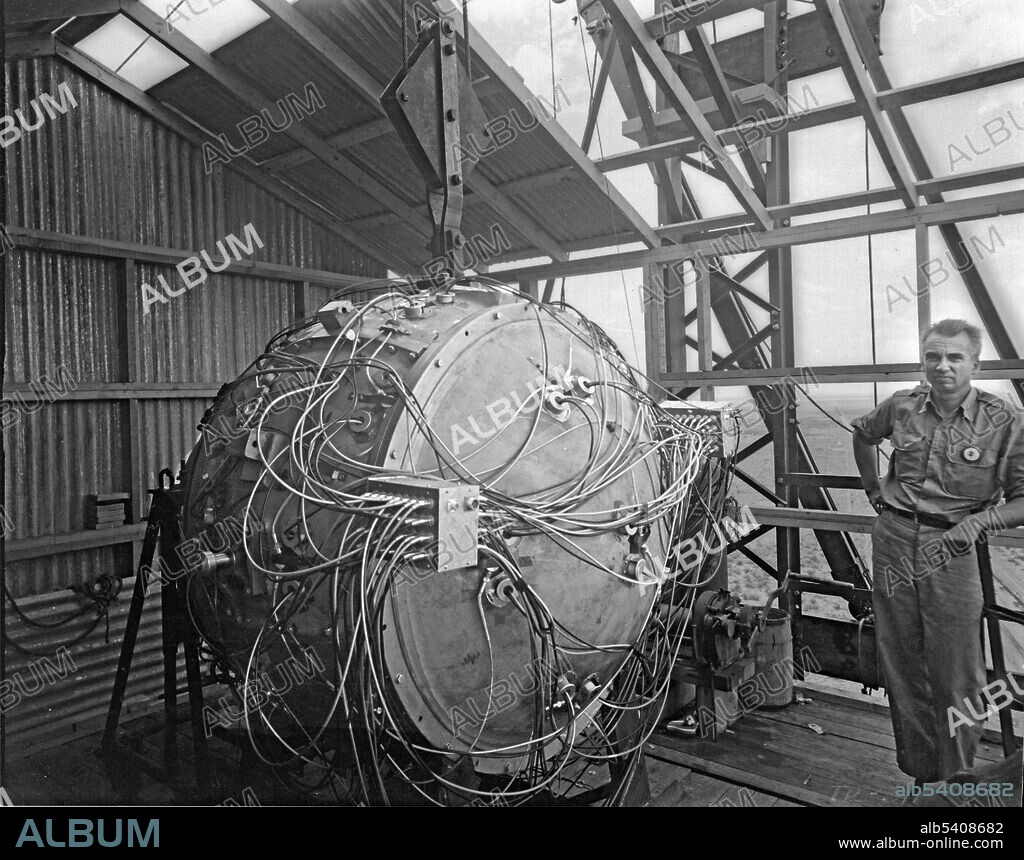 Bradbury stands next to the partially assembled Gadget atop the test tower. Assembly of the nuclear capsule began on July 13 at the McDonald Ranch House, where the master bedroom had been turned into a clean room. The polonium-beryllium "Urchin" initiator was assembled, and Louis Slotin placed it inside the two hemispheres of the plutonium core. Cyril Smith then placed the core in the uranium tamper plug. Air gaps were filled with 0.5-mil (0.013 mm) gold foil, and the two halves of the plug were held together with uranium washers and screws which fit smoothly into the domed ends of the plug. The completed capsule was then driven to the base of the tower. Norris Edwin Bradbury (May 30, 1909 - August 20, 1997) was an American physicist. He served as director of the Los Alamos National Laboratory for 25 years (1945-70), succeeding J. Robert Oppenheimer, who personally chose Bradbury for the position of director after working closely with him on the Manhattan Project. During the war he was in charge of the final assembly of "the gadget", detonated in July 1945 for the Trinity test. He oversaw the transition of the laboratory from WWII through the Cold War. The Bradbury Science Museum is named in his honor.