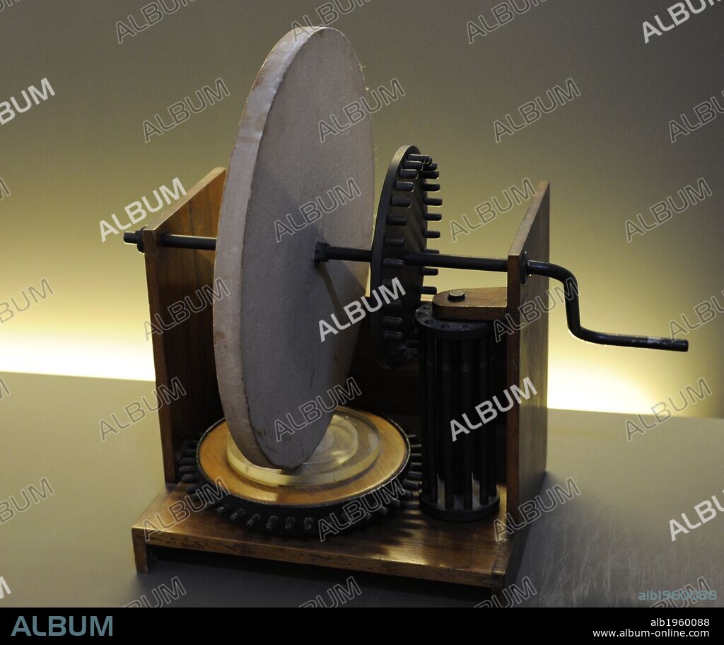 Molienda de Espejos cóncavos. Artilugio dibujado por LEONARDO DA VINCI (S. xv). Interpretación diseñada por Mario Alberto y Vittorio Somenzi, 1957. El modelo consta de un disco montado sobre un bastidor de madera. El disco se apoya verticalmente sobre una superficie cóncava plexiglás (que simula el espejo a pulir), y se inserta en un árbol de transmisión, acoplado a una rueda dentada que a su vez engrana con el piñón. Máquina que sirve para el rectificado de los espejos. Museo Nacional de la Ciencia y Tecnología Leonardo Da Vinci. Milán. Italia.