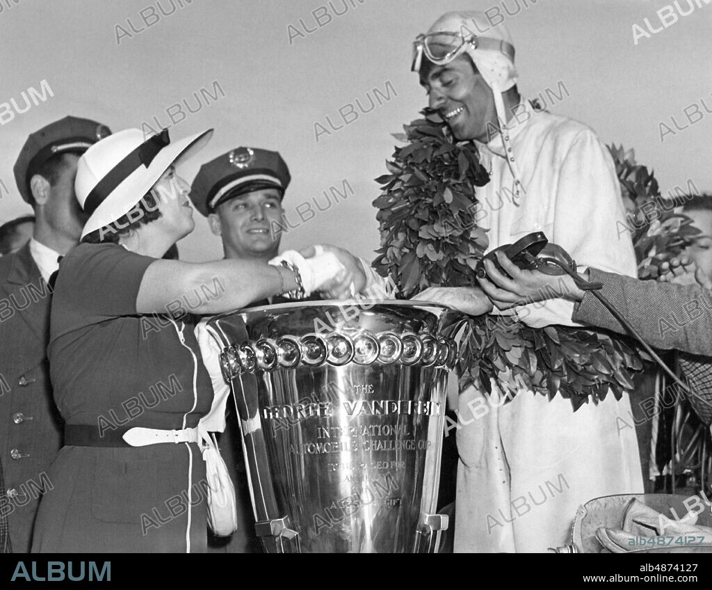 LONG ISLAND USA 1937-07-05. Orig. caption ... GERMAN WINS VANDERBILT CUP RACE Mrs. Margaret Emerson, mother of George Vanderbilt, donor of the cup, congratulating Bernd Rosemeyer, winner of the Vanderbilt Cup Race at Roosevelt Raceway, Long Island, July 5th. Rosemeyer, driving a 16-cylinder Auto-Union, finished in 3 hours and 38 minutes averaging 82,461 miles per hour for the 300-mile run. Photo: ACME / AB Text & Bilder / SVT / Code: 5600 Folder: Rosemeyer, Bernd B Rosemeyer, 1909-1938, German racing driver, died in an accident while trying to break speed record 28/1 1938. Winners Winners Awards Awards Wreaths Trophies persons: BERND ROSEMEYER; MARGARET EMERSON sites: USA; GERMANY *.