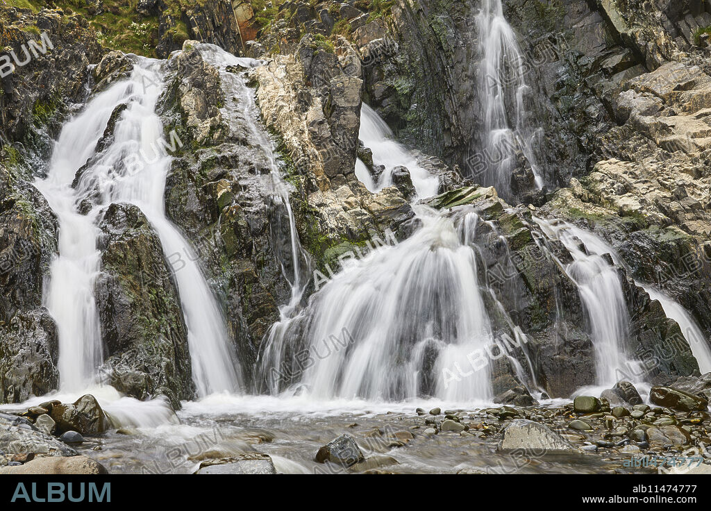 Waterfall pouring down a rocky cliff, with blurred motion, resulting from a slow shutter speed; at Welcombe Mouth, Hartland, north Devon, England, United Kingdom, Europe.
