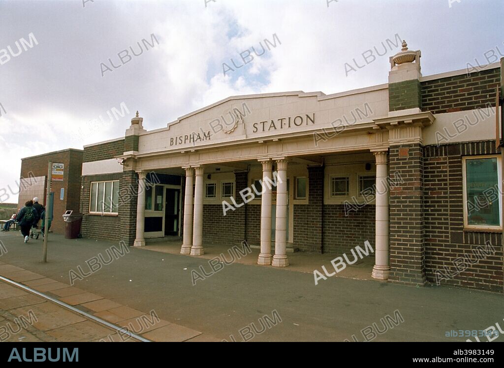Bispham Station, Blackpool, Lancashire, 1999. The facade of the station with the tram lines are shown on a slightly overcast day. To the left are two figures walking away. Blackpool is famous for the tramway which runs along its promenade and Bispham Station is a major halt on the route.