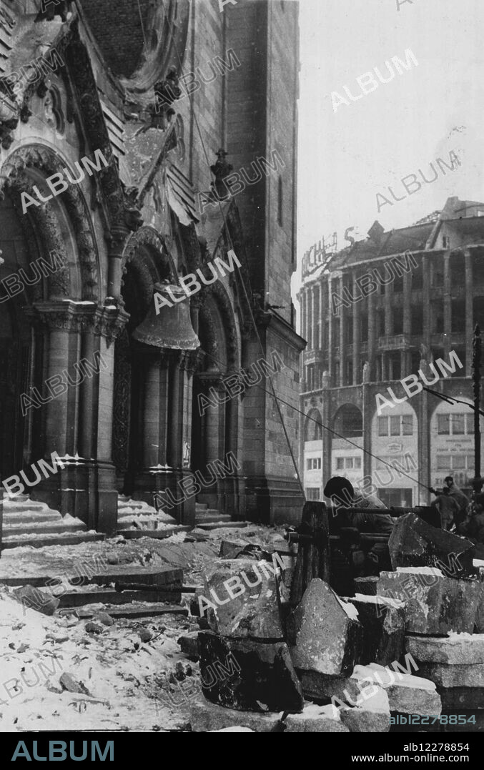 Berlin Church To Be Dynamited -- German workmen removing the only undamaged bell form the belfry of the bombed-out Gedachtniskirche (***** Church) a towering landmark of Roman architecture at the foot of the Kurfurstendamm (in the British sector of the city) which is to be blown up by a German demolition crew shortly. Only the shell of the once famous building remains standing. It was severely damaged ***** air raids in the war. March 12, 1949.