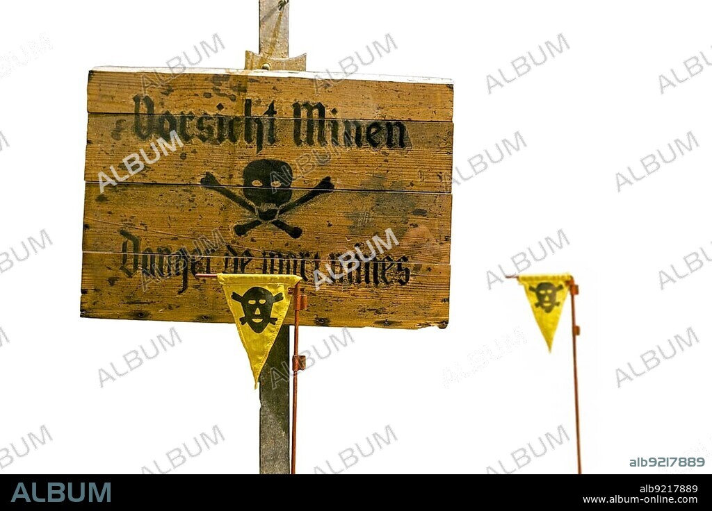 German World War Two wooden Vorsicht Minen, Caution Land Mines warning sign and marker flags marking minefield, mine field against white background.