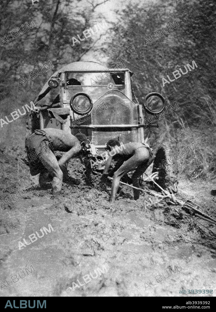 Stuck in the mud, Bulawayo to Dett, Southern Rhodesia, c1924-c1925 (1927). A print from Cape to Cairo, by Stella Court Treatt, George G Harrap & Company Ltd, 1927. The book was an account of the first successful journey by motor vehicle from Cape Town to Cairo, accomplished by Stella Court Treatt and her husband, Major Chaplin Court Treatt, in 1924-1926. Heavy rains and mud meant the approximately 400 mile section of the journey between Bulawayo and Victoria Falls took four months to complete.