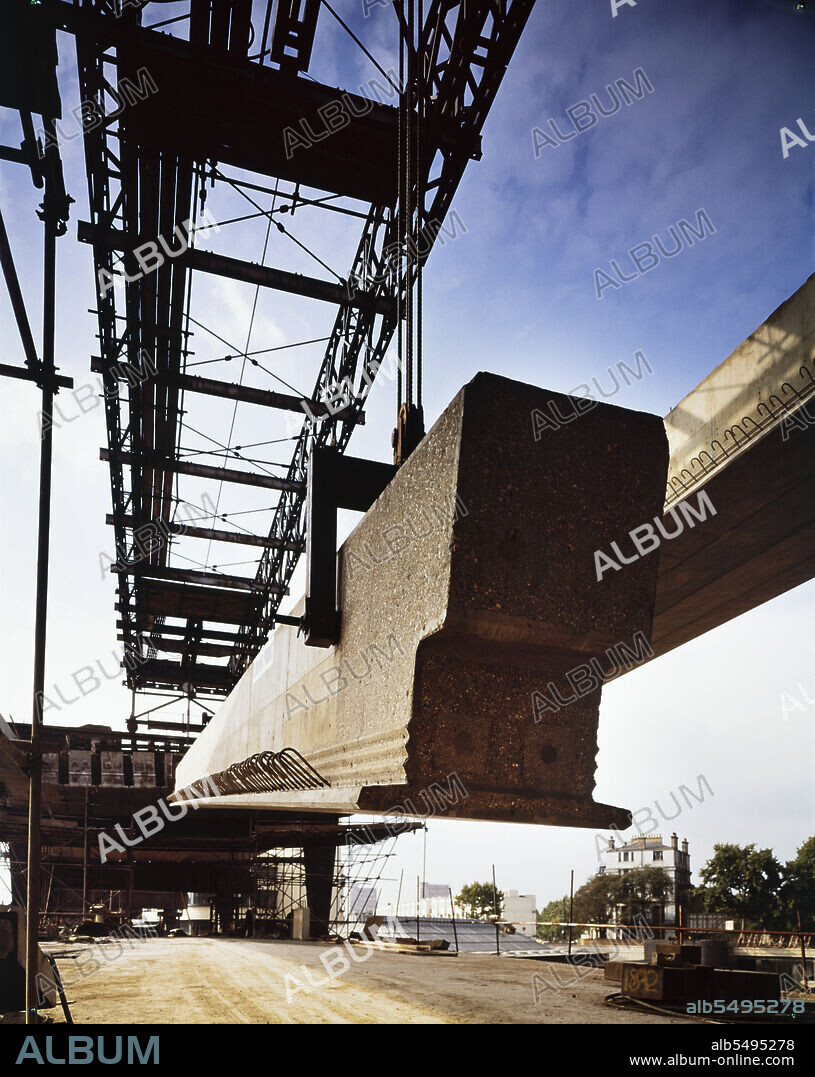 JOHN LAING PLC. Westway Flyover, A40, Paddington, City of Westminster, London, 02/10/1969. The gantry lifting a deck beam into position during construction of the Westway Flyover where it spans the canal leading to Paddington Basin. Work on site for the Western Avenue Extension began on 1st September 1966, and the Westway as it became known was officially opened on 28th July 1970. The elevated highway connecting the A40 at White City to Marylebone Road in Paddington, at around 2 ½ miles, was the longest in Europe. The construction was organised into six sections. Sections 1, 4, 5 & 6 formed the main flyover into central London with Sections 2 & 3 being the West Cross Route, running south from the junction in Section 1 near Latimer Road to Shepherds Bush. Different construction techniques were used for Section 6; the road deck was formed from longitudinal beams rather than sections spanning the width of the carriageway. As part of the project, Harrow Road was divided and the northbound carriageway carried on a second deck beneath the main Westway Flyover. This photograph was taken at grid reference TQ2639081701.
