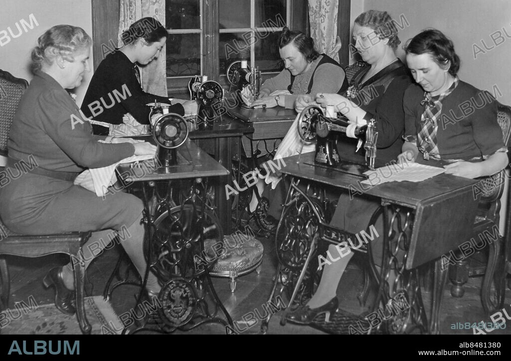 Orig. bildtext... SYSTUGA FÖR ASTRIDBARNEN. På den belgiska legationen i Villagatan 13 surrar symaskinerna flitigt hela dagarna. Det är prinsessan de Croy /längst t.v. på bilden/ som i spetsen för några damer i belgiska kolonien i Stockholm syr kläder för Astridbarnen, som skola komma till Sverige. 21-3-42 Anm. Belgiens svenskfödda drottning Astrid bildade 1934 hjälporganisationen Comité National des Secours för fattiga och nödlidande. Barnkläder Profiler Sy Symaskiner Sömnad Textilier Trampmaskiner Tyg Välgörenhet CD628 sites: STOCKHOLM;SVERIGE;BELGIEN*.
