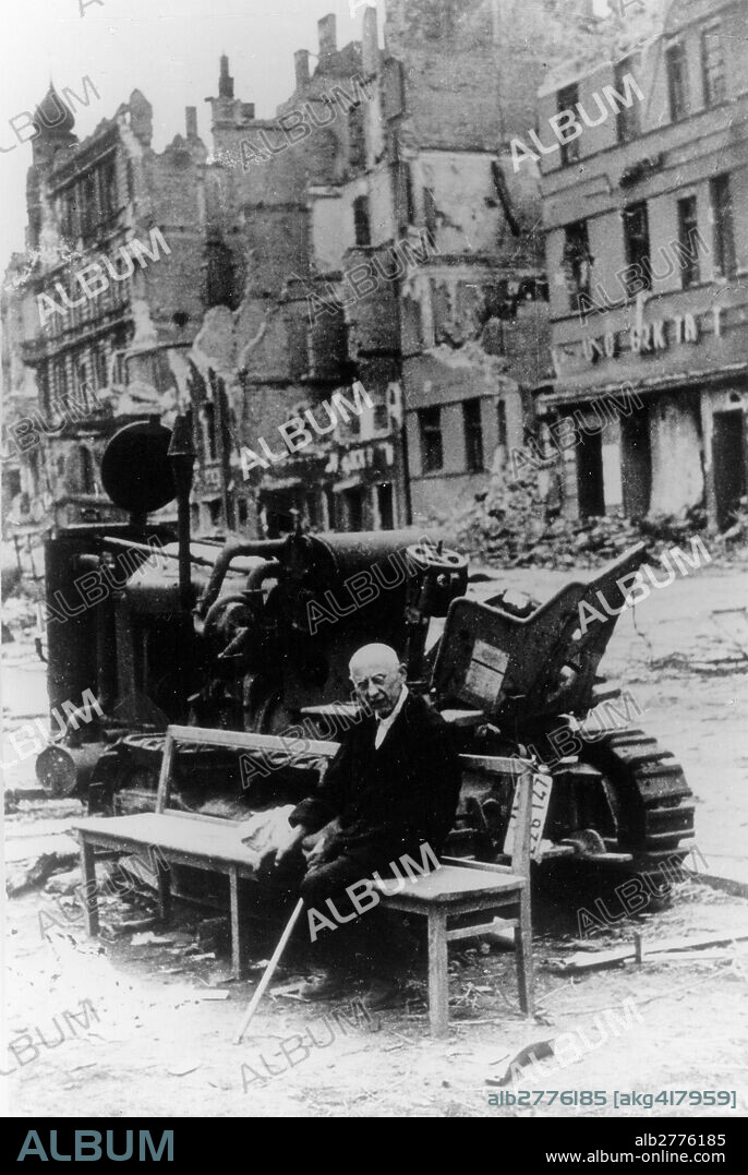 Berlin / End of the war 1945: Greater Berlin under Soviet miltary control.-An old man sits on a bench in front of abandoned machinery in a destroyed street.-Photo, May 1945 (Novosti).