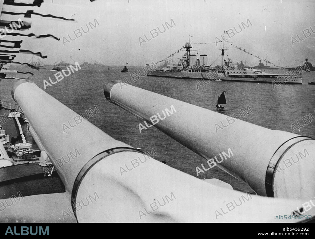 Fleet At Spithead For Grand Coronation - Review By The King - A fine of the H.M.S. Hood and other ships of the Fleet seen from the H.M.S. Repulse over the latter's huge guns, at Spithead ready for the review.The Fleet is now assembling at Spithead where the great Naval Review by King George VI will take place next Thursday. Ships of the navies of the world are represented and next Thursday's spectacular sight will be watched by many thousands. May 17, 1937. (Photo by Keystone).
