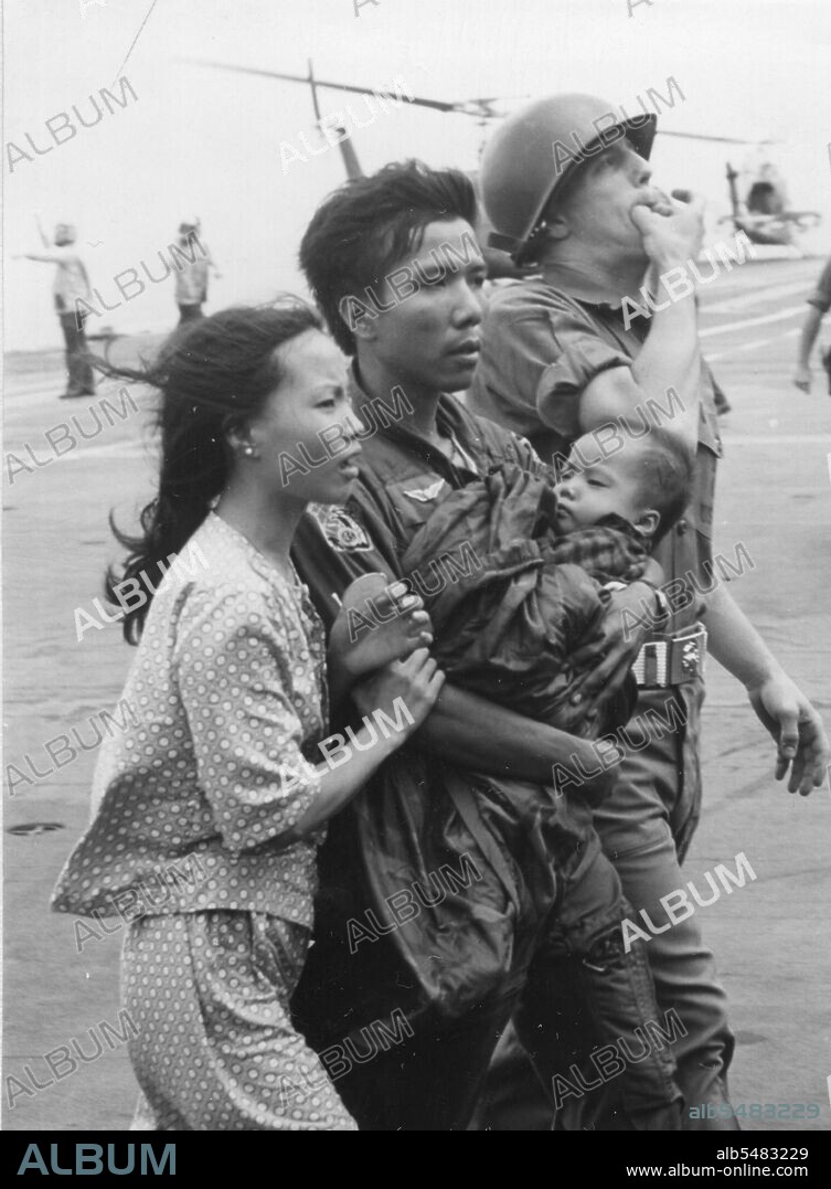OPERATION FREQUENT WIND - A South Vietnamese helicopter pilot and his family, safely aboard the USS HANCOCK, are escorted by a Marine Security Guard to the refugee area during the evacuation of Saigon, Republic of Saigon. April 29, 1975.
