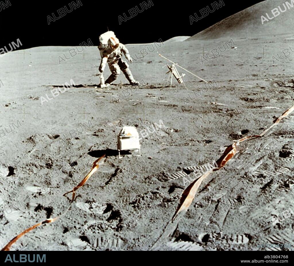 Astronaut David Scott, commander of the Apollo 15 mission, picks up a cordless drill to take samples on the surface of the Moon on August 1, 1971. Mt. Hadley is seen rising in the right background. Scott uses a battery-powered drill during the Apollo 15 mission. The drill was used to create a hole 2.4 meters deep in the lunar surface. A probe was planted in this hole to measure heat flowing from the Moon's interior. The small box in the foreground is a solar wind spectrometer, also part of the Apollo Lunar Surface Experiment Package (ALSEP). During their 67-hour stay on the Moon, they made three excursions totaling 18 hours 35 minutes. This included the first use of the Lunar Roving Vehicle (LRV).