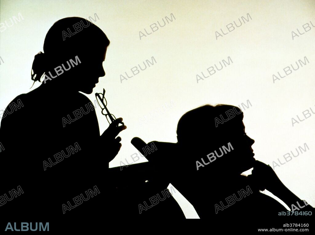 Counseling. Silhouette view of a woman patient lying on a couch during a one-to-one counseling session. The female psychoanalyst is seated behind the patient & is listening intently. This form of therapy is aimed at helping a person address a particular problem (such as bereavement, drug & alcohol addiction) and to provide support during life crises. The counselor or psychologist encourages the patient to discuss their feelings, experiences or problems.